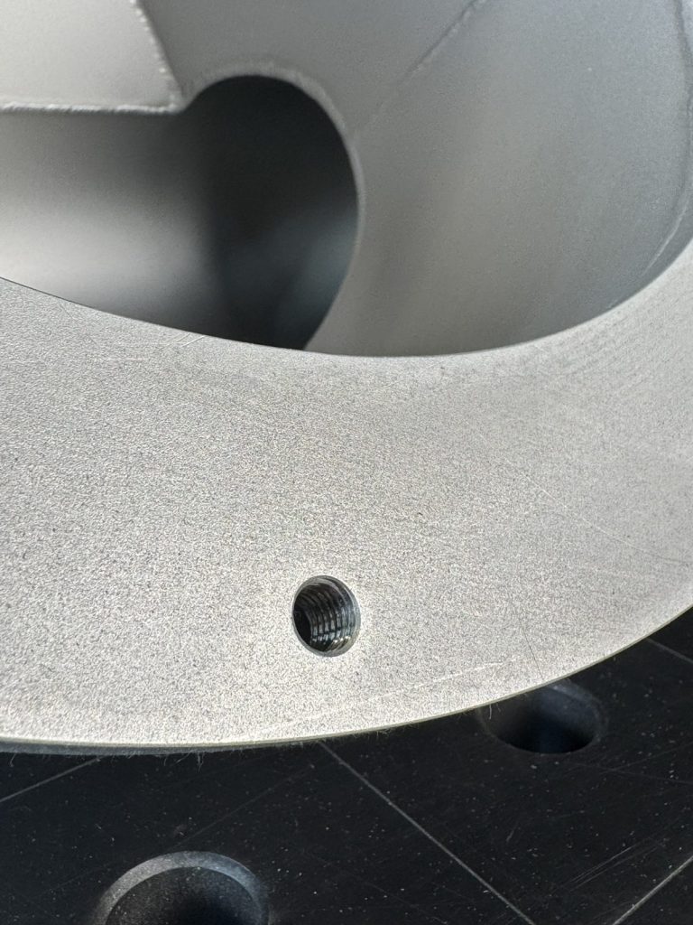 Nahaufnahme einer glasperlgestrahlten Edelstahloberfläche mit Gewindebohrung